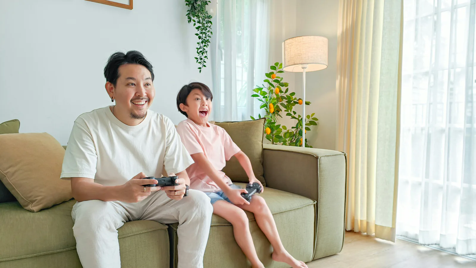 A father and son playing a game on the couch at home